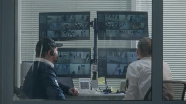 保安人员坐在监控室里 观看计算机显示器上显示的摄像头视图 一个用数字平板电脑 另一个用对讲机交谈 高科技安全 社会安全 — 图库视频影像