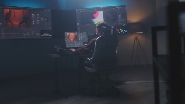 女性映画編集者やカラーリストは 現代のスタジオでコンピュータ上の色のグレーディングを行います Rgbカラー補正グラフィックバーと壁にプログラムインターフェイスを持つ大きなモニター ビデオポストプロダクション 手持ち — ストック動画