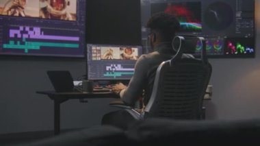 Afrikalı Amerikalı renklendirici video düzenleme yazılımında renk derecelendirme yapıyor. Uzay yolculuğu film görüntülerine ve RGB renk düzeltme çubuğuna sahip birden fazla monitör. Modern stüdyoda post prodüksiyon.
