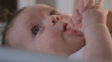 Beyaz takım elbiseli beyaz çocuk portresi sabahları beyaz çarşaflarla beşikte yatar. Sevimli ve tatlı çocuk elleriyle oynuyor. Bebek, çocukluk, ebeveynlik, hayat ve aile kavramı.