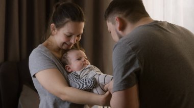 Sevimli bir annenin kucağında güzel bir kız ya da oğul tutmasının portresi. Babam kreşte bebek kıyafetleri içinde bebek bacaklarıyla oynuyor. Çocukluk kavramı, ebeveynlik, aile ve aşk. Uzaklaştır.