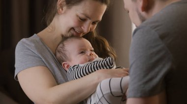 Sevimli bir annenin kucağında güzel bir kız ya da oğul tutmasının portresi. Babam kreşte bebek kıyafetleri içinde bebek bacaklarıyla oynuyor. Çocukluk kavramı, ebeveynlik, aile ve aşk. Uzaklaştır.