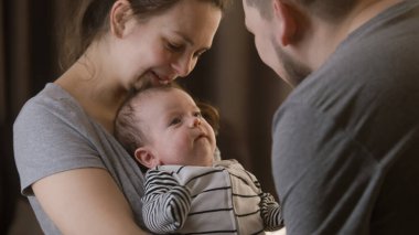 Sevimli bir annenin kucağında güzel bir kız ya da oğul tutmasının portresi. Babam kreşte bebek kıyafetleri içinde bebek bacaklarıyla oynuyor. Çocukluk kavramı, ebeveynlik, aile ve aşk. Uzaklaştır.
