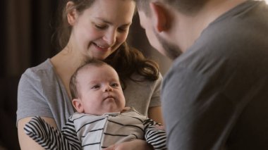 Sevimli bir annenin kucağında güzel bir kız ya da oğul tutmasının portresi. Babam kreşte bebek kıyafetleri içinde bebek bacaklarıyla oynuyor. Çocukluk kavramı, ebeveynlik, aile ve aşk. Uzaklaştır.