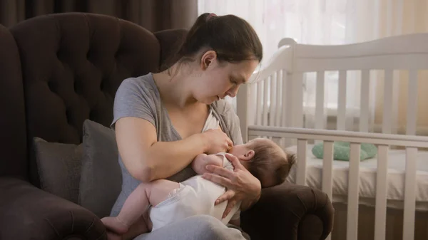 아기를 보살펴 어머니는 아기에게 모유를 먹이고 근처에 안락의자에 앉는다 여자들은 — 스톡 사진