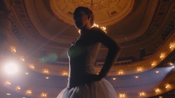 白いチュチュのバレエ女性ダンサーは 舞台上で振付を訓練し ショーを開始する準備をします パフォーマンスのリハーサルでバレリーナ 照明付きの劇場ホール 古典バレエ芸術 — ストック動画