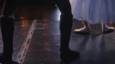 Sahnede sahne ışıkları altında dans eden ve gösteri için hazırlanan bale dansçılarının yakın çekim görüntüleri. Koreografi provasında kadın ve erkek pratik yapıyor. Klasik bale gösterisi.