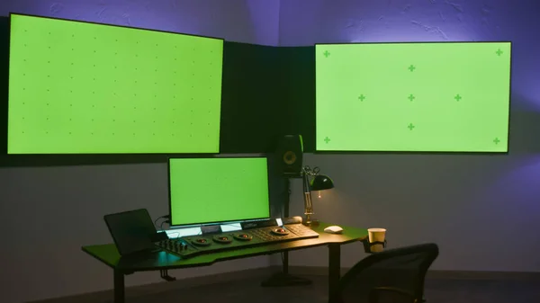 Studio with modern equipment for video or film color grading. Computer, digital tablet and big screens showing program interface, video footage. Color correction control panel. Green screen, chromakey