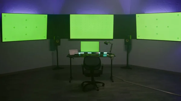 Studio with modern equipment for video color correction. Computer, digital tablet and big screens showing program interface, video footage. Color grading control panel. Post production. Green screen.