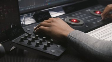 Afrika kökenli Amerikalı video editörünün elleri kapalı. Renk derecelendirme kontrol paneli ile modern tasarım ile çalışıyor. Renkçi, film sonrası film için renk düzeltmesi yapıyor. Profesyonel ekipman.