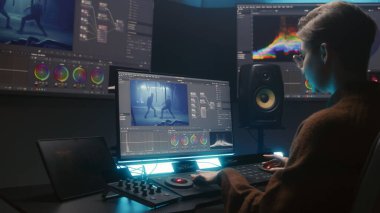 Kadın editör renk derecelendirme kontrol paneli kullanır, video düzenler, stüdyoda bilgisayar ve tablet üzerinde film renk düzeltmesi yapar. Film görüntüleri ve RGB tekerlekleri monitörde. Uygulama arayüzü olan büyük ekranlar.