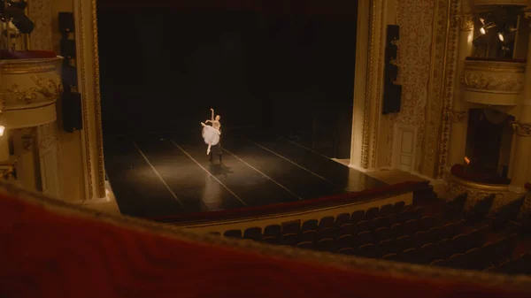 stock image Establishing shot of ballet dancers preparing theatrical dance performance. Man and woman practice choreography on classic theater stage. Classical ballet dance. Rows of seats. Dramatic lighting.