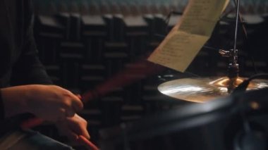 Erkek müzisyenin davul çalarkenki yakın çekimi. Davulcu, müzik grubu için ses kayıt stüdyosunda şarkı kaydetti. Müzik kayıt odasında çalış. Müzik üretim konsepti.