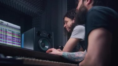 Ses mühendisi ve erkek şarkıcı müzik kayıt odasında konuşur ve şarkı yaratır. Bilgisayar ekranı DAW yazılım arayüzünü ses parçalarıyla gösteriyor. Ses kayıt stüdyosunda çalışıyorum. Müzik üretim konsepti.