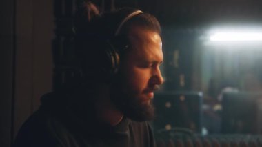 Kulaklıklı erkek müzisyen portresi davul çalıyor. Ses kayıt stüdyosunda profesyonel davulcu şarkısı. Ses mühendisi arka planda çalışıyor. Müzik kayıt odası. Müzik üretim konsepti.