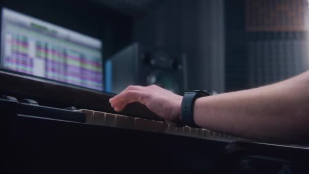 オーディオエンジニア プロデューサーは音楽制作にMidiコントローラー デジタル電気ピアノを使用します サウンドトラックとDawソフトウェアインターフェイスを示す画面 録音スタジオだ 音楽制作 閉じろ — ストック動画