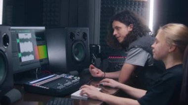 Kadın ses mühendisi ve müzisyen müzik kayıt odasında şarkı yarattılar. Bilgisayar ekranı DAW yazılım arayüzünü ses parçasıyla gösteriyor. Ses kayıt stüdyosundaki modern ekipmanlar. Müzik üretimi.