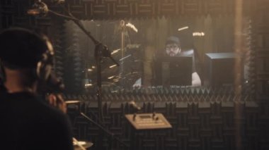 Afrikalı Amerikalı şarkıcı ve gitarist ses geçirmez odada yeni parça kaydetti. Deneyimli ses mühendisi müzik grubu çalışmalarını ses kayıt stüdyosunda inceliyor. Müzik üretimi kavramı. Arka plan.