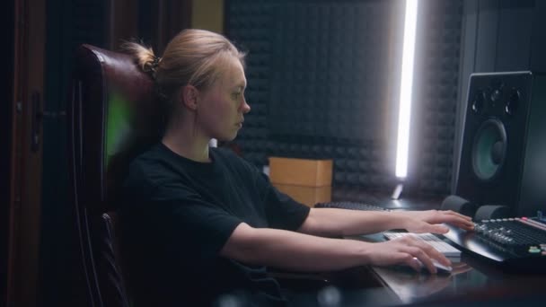 女性オーディオエンジニア ミュージシャン プロデューサーは Midiコントローラー ミキシングボードを使用して 音楽を作成するための最新の機器で曲やDjセットを作成します 録音スタジオで働く 音楽制作コンセプト — ストック動画