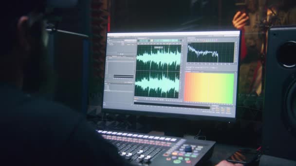 サウンドエンジニア プロデューサーは制御混合面を使用しています コンピューター画面には 音楽制作用のDawソフトウェアインターフェースが表示されます シンガーは防音室で歌を録音します 録音スタジオだ 音楽制作 — ストック動画