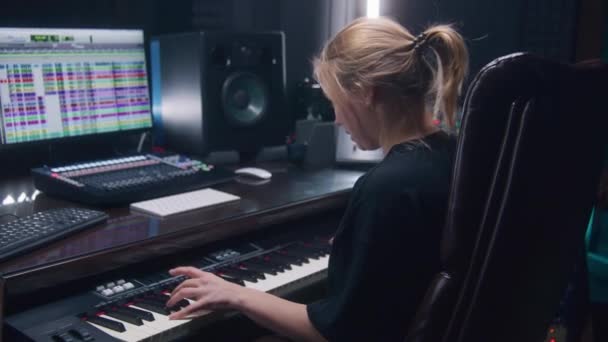 女性のサウンドエンジニア ミュージシャンは音楽を作成するためにMidiコントローラー デジタル電気ピアノを使用します コンピューター画面には Dawソフトウェアインターフェースとサウンドトラックが表示されます 録音スタジオ 音楽制作 — ストック動画