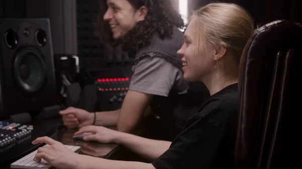 女性のオーディオエンジニアとミュージシャンは 音楽録音室で曲を作成します サウンドトラックとDawソフトウェアインターフェイスを示すコンピュータ画面 録音スタジオの近代的な機器 音楽制作 — ストック写真