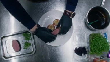 Şef yemek sunumu yapıyor. Aşçı erimiş peynirli fırında tatlı patatese sulu ızgara biftek koyar. Gastronomik sanat. Profesyonel gurme mutfağı olan bir restoran. Kamu hizmeti.