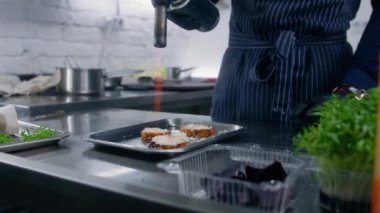 Şef mutfakta lezzetli vejetaryen yemeği pişirir. Erkek aşçı fırında pişmiş patatesle peyniri gaz sobasıyla eritiyor. Profesyonel gurme mutfağı olan bir restoran. Kamu hizmeti. Yakınlaştır.