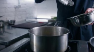 Önlüklü profesyonel aşçı ravioli 'yi mutfak maşasıyla tencereye kaynar suyla koyar. Deneyimli aşçı gurme mutfağıyla restoranda gastronomi yemekleri yapar. Kamu hizmeti kavramı.