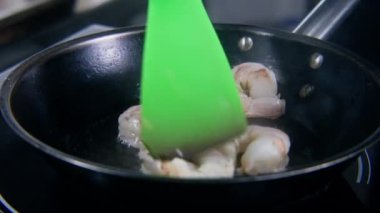 Erkek aşçı kızartma tavasına karides koyar, yağlı ve tuzlu. Şef lezzetli yemekler pişirir. Lokanta ya da kafe mutfağında aşçılık. Profesyonel gurme mutfağı. Kamu hizmeti.