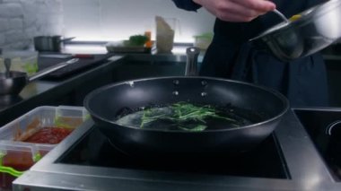 Aşçı ravioli 'yi tereyağı ve biberiyeyle birlikte elektrikli ocağa koyar. Aşçı misafirler için yemek hazırlar. Gurme yemekleri yapma süreci. Restoran mutfağında çalışma fikri. Kapat..
