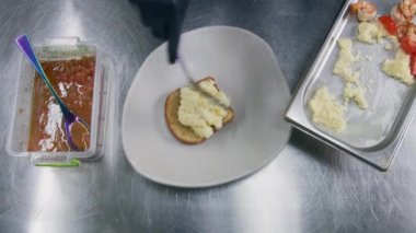 Şef yemek sunumu yapar. Aşçı kızarmış ekmeğin üzerine çırpılmış yumurta, avokado ve kızarmış karides koyar. Lokanta ya da kafe mutfağında aşçılık. Profesyonel mutfağa. Kamu hizmeti. Yakınlaştır