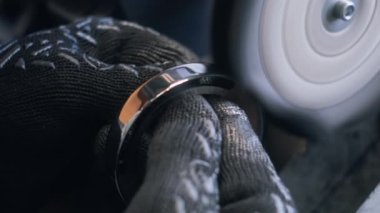 Erkek çalışanın, metal işçiliğini düzeltirken disk ile öğütme makinesinde çalışmasını yakından çek. Fabrikada sinema lensleri üretiliyor. Üretim, endüstriyel ve teknoloji kavramı.