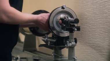 ZAPORIZHYA, UKRAINE - 25 Mart 2023: Torna tezgahına kamera için gelecek sinüs lenslerini yerleştiren profesyonel erkek teknisyene yaklaş. Sinema lenslerinin üretimi. Konsept