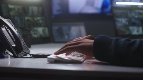 键盘上的男性安全操作员类型 非裔美国人在监测中心工作 背景上有闭路电视摄像头镜头的计算机和数字平板屏幕 跟踪系统 手靠紧 — 图库视频影像