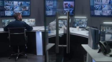 Çeşitli operatörler yapay zeka yüz taramasıyla CCTV kameralarını kontrol ediyor. Güvenlik izleme merkezi çalışanları. Güvenlik kameraları bilgisayar monitörlerinde ve büyük dijital ekranlarda görüntüleniyor..