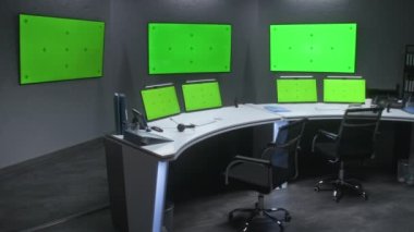 CCTV kameralarını izlemek için güvenlik izleme merkezinde çalışma alanı. Masadaki bilgisayar monitörleri ve duvardaki büyük dijital ekranlar ve güvenlik kamerası görüntülerini gösteren kromakey. Yeşil Ekran.