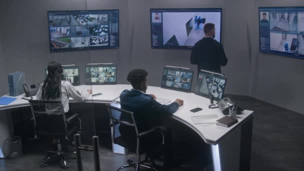 多族裔安全官员使用人工智能面部扫描对闭路电视摄像机进行监测 多个大屏幕与显示的安全摄像头 监视室的团队合作 跟踪和社会安全 — 图库视频影像