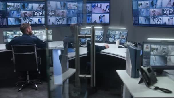 役員の多様なチームは Ai顔認識とCctvカメラを監視します 従業員はセキュリティコントロールセンターで働いています 監視カメラのビデオ映像を示すコンピュータモニタと大きなデジタル画面 — ストック動画