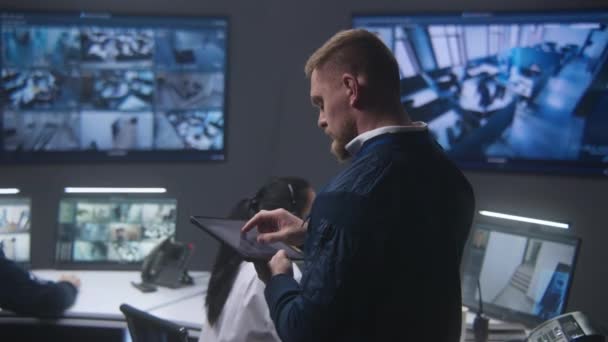 Mężczyzna Kontroluje Kamery Policyjnym Centrum Obserwacyjnym Używa Tabletu Monitory Wiele — Wideo stockowe
