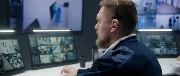 在警察监控中心 男性安全官员使用平板电脑 控制带有人工智能面部识别系统的闭路电视摄像头 电脑显示器和显示安全摄像头镜头的大数字屏幕 — 图库照片