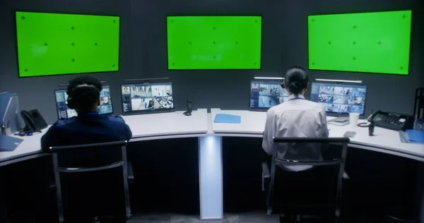 多族裔男女官员控制闭路电视摄像机 员工在安全控制中心工作 显示监控摄像头录像的计算机监视器 带有铬钥匙的大型数字屏幕 — 图库照片