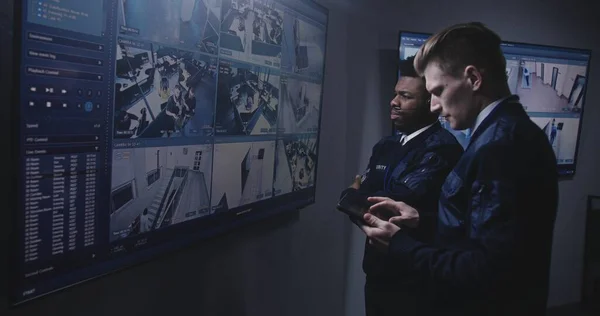 Oficer Ochrony Monitoruje Kamery Przy Użyciu Tabletu Rozmawia Afroamerykańskim Kolegą — Zdjęcie stockowe