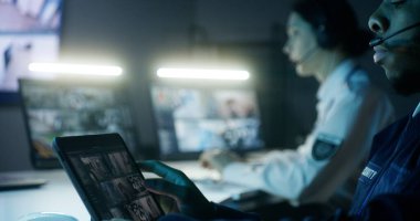 Güvenlik görevlileri güvenlik kameralarını kontrol ediyor. Kadın bilgisayar kullanıyor, Afro-Amerikan erkek güvenlik kamerası görüntülü dijital tablet kullanıyor. İzleme ve izleme sistemi. Sosyal güvenlik kavramı.
