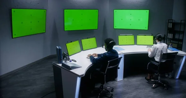 多人種の男性と女性の役員はCctvカメラを制御します 大きなデジタルスクリーンと緑の画面でコンピュータモニタ 監視カメラのビデオ映像を示す — ストック写真