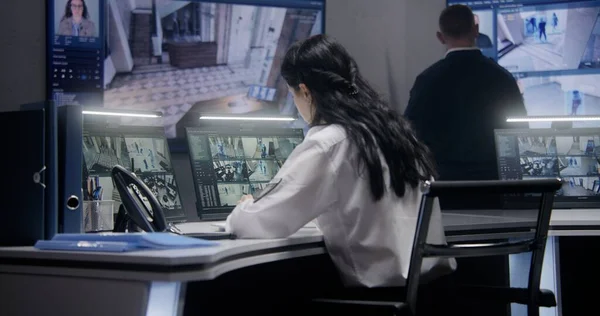 女警官在警察监测中心的计算机上工作 利用平板和大屏幕上的人工智能人脸识别系统来控制监控闭路电视摄像头的多族裔工作者 — 图库照片