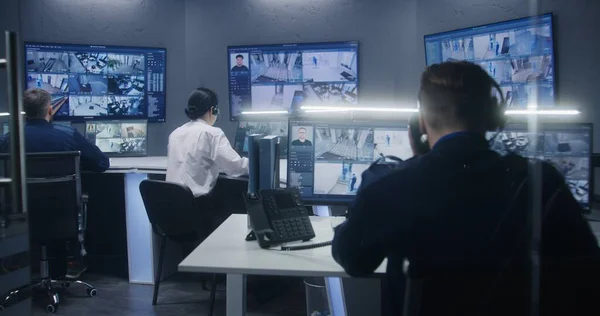 多样化的官员团队使用人工智能面部识别系统观看闭路电视摄像机 员工在安全控制中心工作 显示监控摄像头录像的计算机显示器和大型数字屏幕 — 图库照片