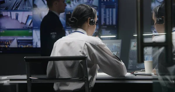 女警官在警察监测中心的计算机上工作 用人工智能面部识别控制闭路电视摄像机 男工用监控摄像头录像观看大的数字屏幕 — 图库照片