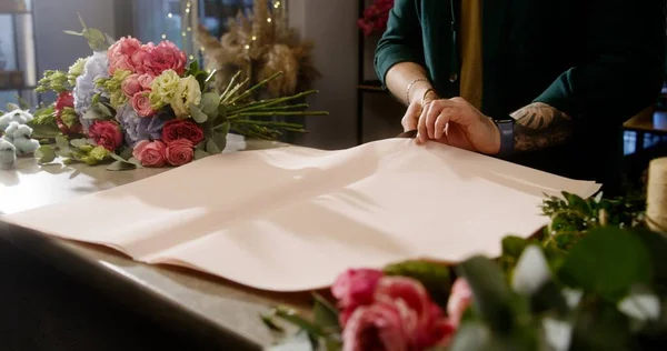 Professionelle Floristin Legt Geschenkpapier Auf Den Tisch Und Schneidet Mit — Stockfoto