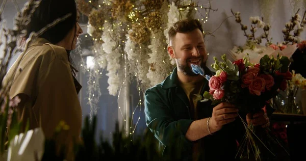 Мужчина Флорист Собирает Цветы Покупательницы Украшает Оберточной Бумагой Разговаривает Ней — стоковое фото